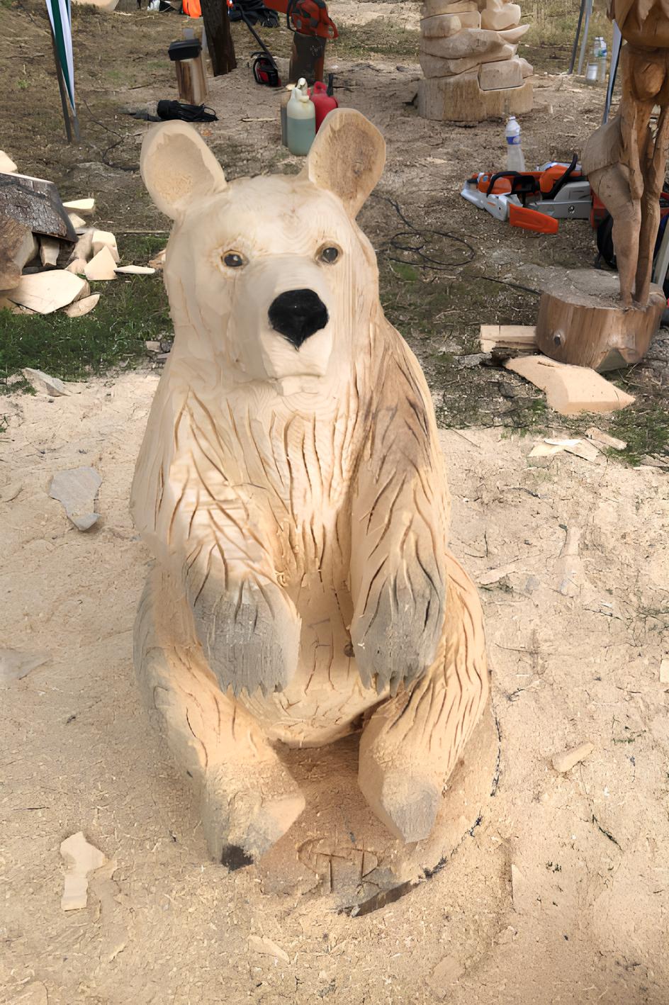 Sculpture sur bois d'un ours dressé sur ses pattes arrière, œuvre de Sébastien Steffen. Position dynamique sur un socle en bois.