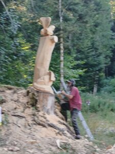 Chantier de sculpture sur bois en direct, vue de profil de l'artiste à l'œuvre.