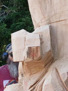 Gros plan sur le travail de précision à la tronçonneuse dans l'atelier en extérieur.