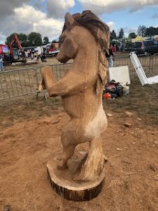 Vue de profil d'une sculpture détaillée de cheval en bois brut par Sébastien Steffen.