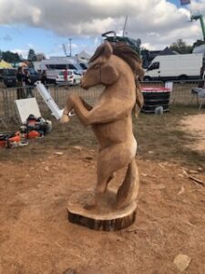 Sculpture d'un cheval cabré sur son socle en bois au milieu de l'événement La petite Angevine.