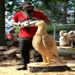 sculpture sur bois d'un aigle majestueux dans un parc, réalisée à la tronçonneuse